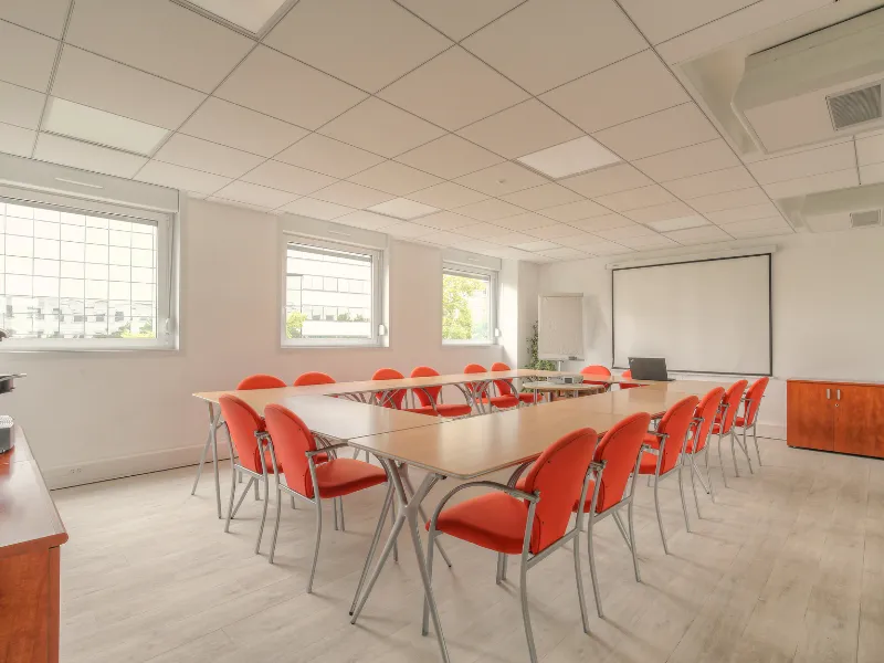Espace de travail collaboratif et salle de séminaire spacieuse avec lumiÚre naturelle et mobilier modulable.